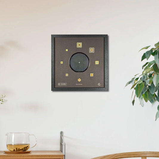 Decorative wall art piece on a white wall with a wooden cabinet and plant in the foreground.