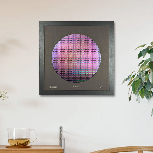 Framed artwork with a circular design on a wall in a room with a wooden cabinet and plant.