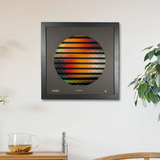 Framed abstract artwork on a wall with a wooden cabinet and plant in the foreground.