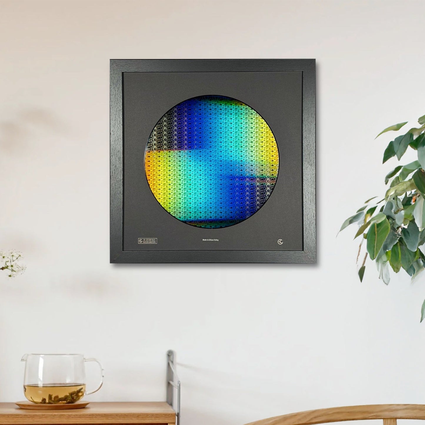 Framed artwork with a colorful circular design on a wall in a room with a wooden cabinet and plant.
