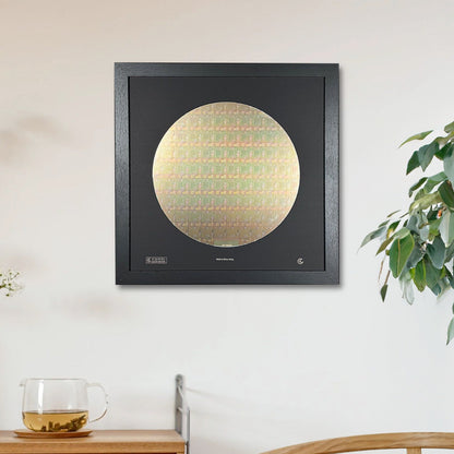 Framed artwork of a gold circle on a black background in a room with a wooden cabinet and plant.