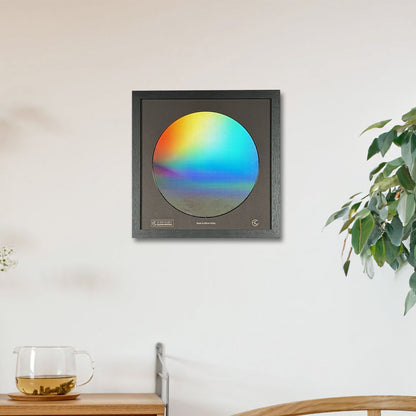 Framed artwork with a colorful circle on a wall in a room with a wooden cabinet and plant.