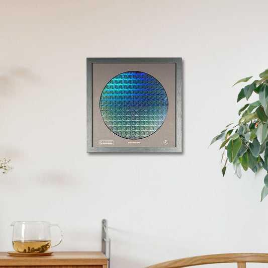 Framed artwork with a circular design on a wall in a room with a wooden cabinet and plant.